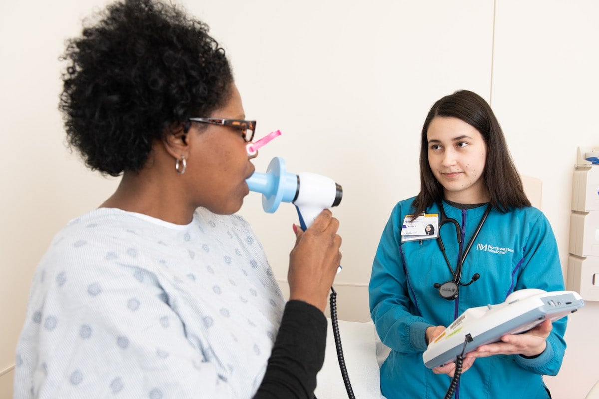 A woman uses a spirometer at the doctor’s office.