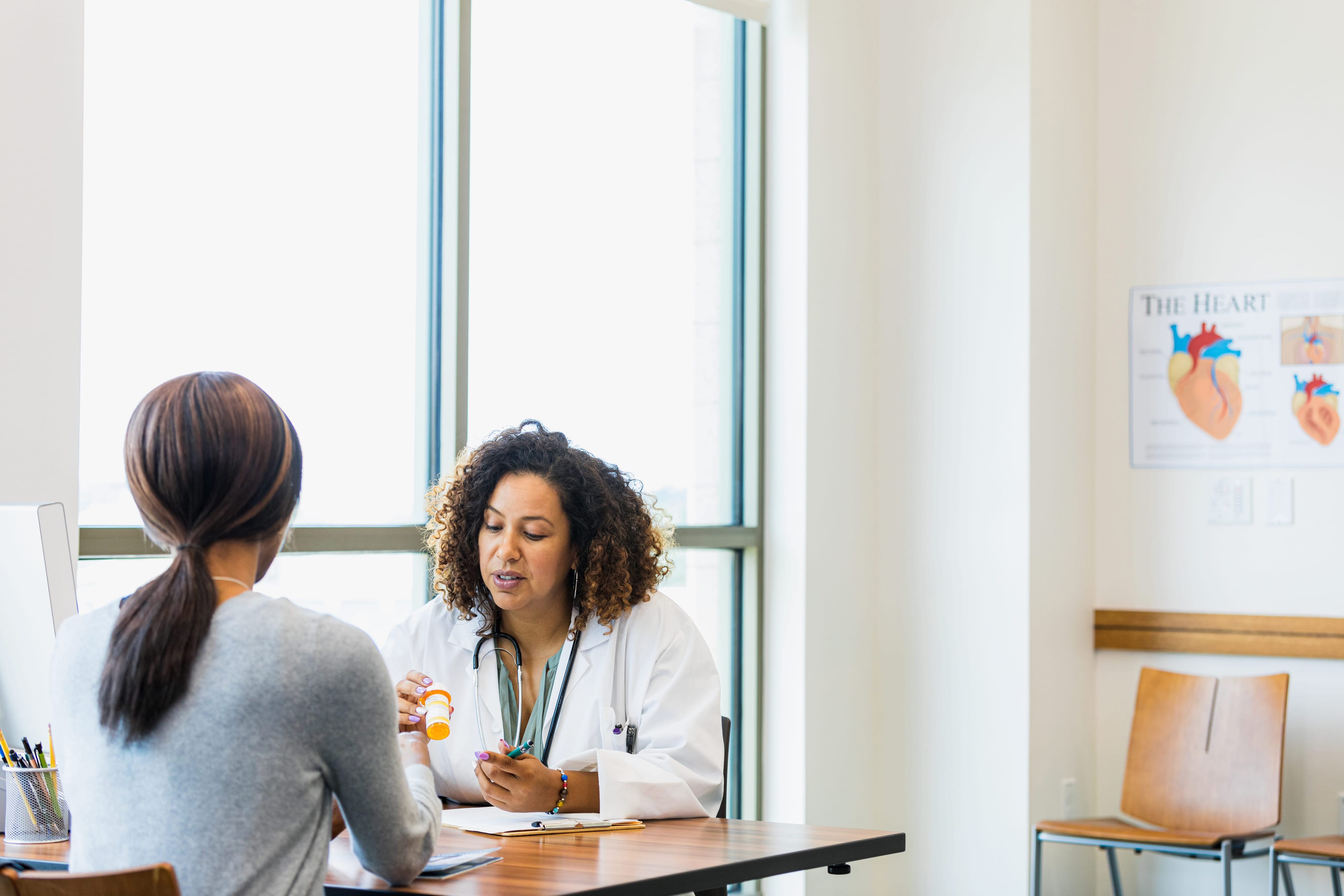 A doctor showing a medicine to a patient while they sit in her office. 