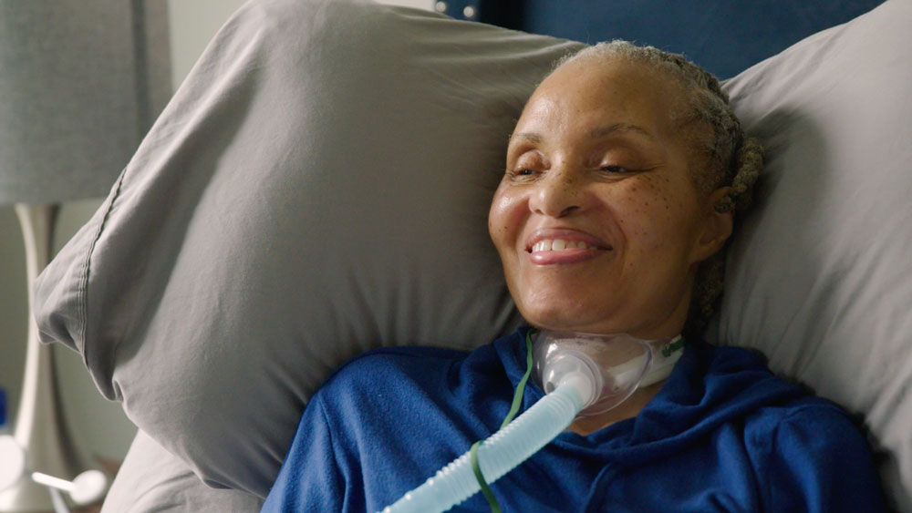 A smiling woman with a trach.